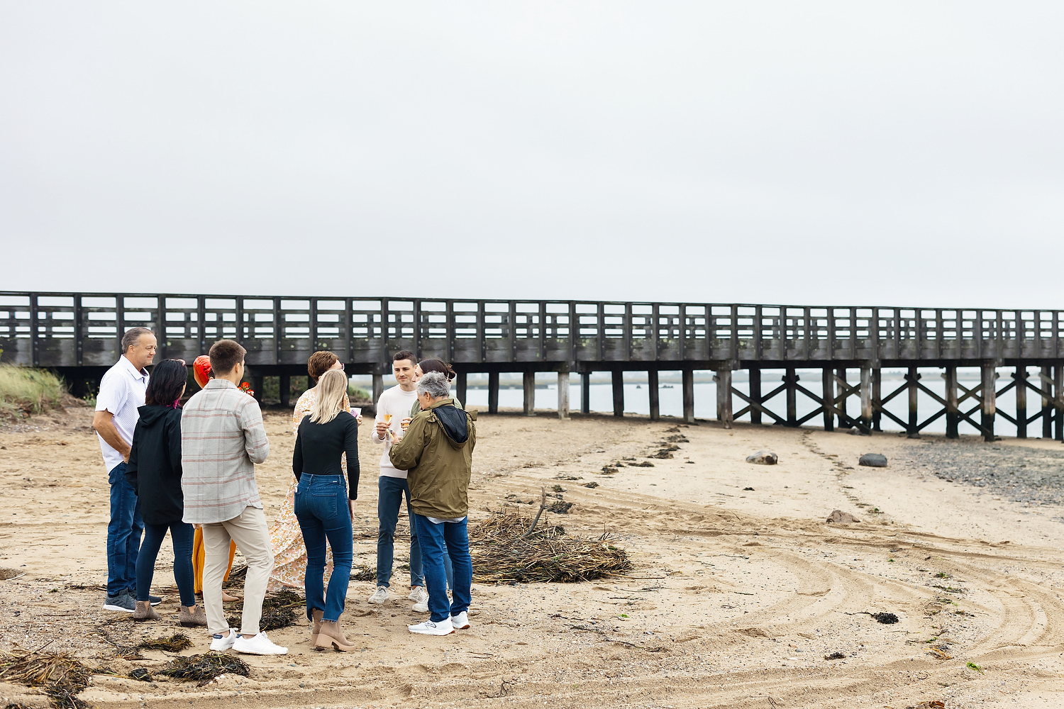 Family and friends cheering under umbrellas at Duxbury Beach proposal celebration