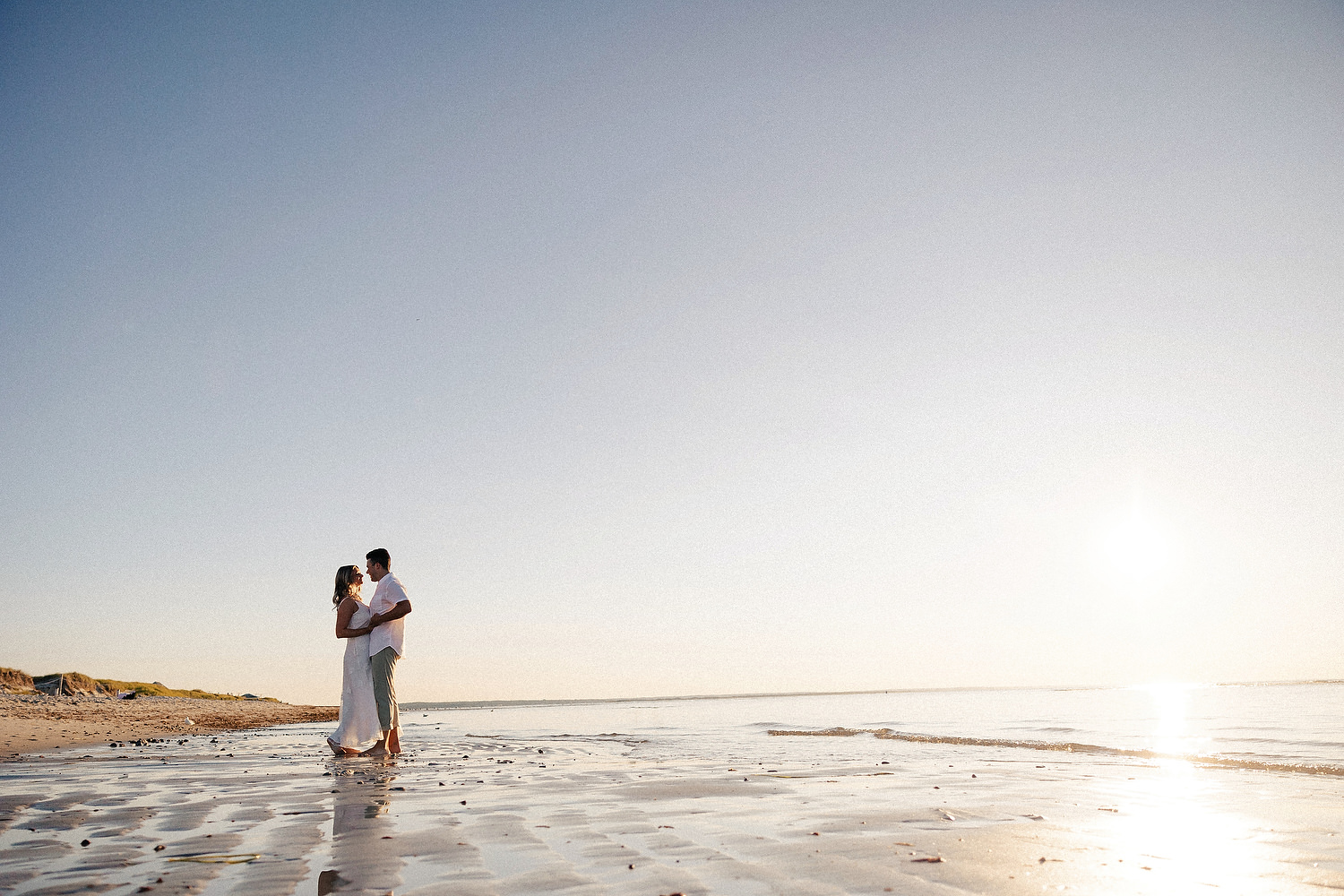 Silhouette of engaged couple walking toward horizon at Mayflower Beach