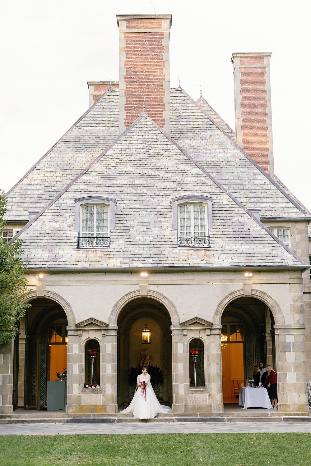 The bride is walking down the aisle through the stone archway at Glen Manor House.